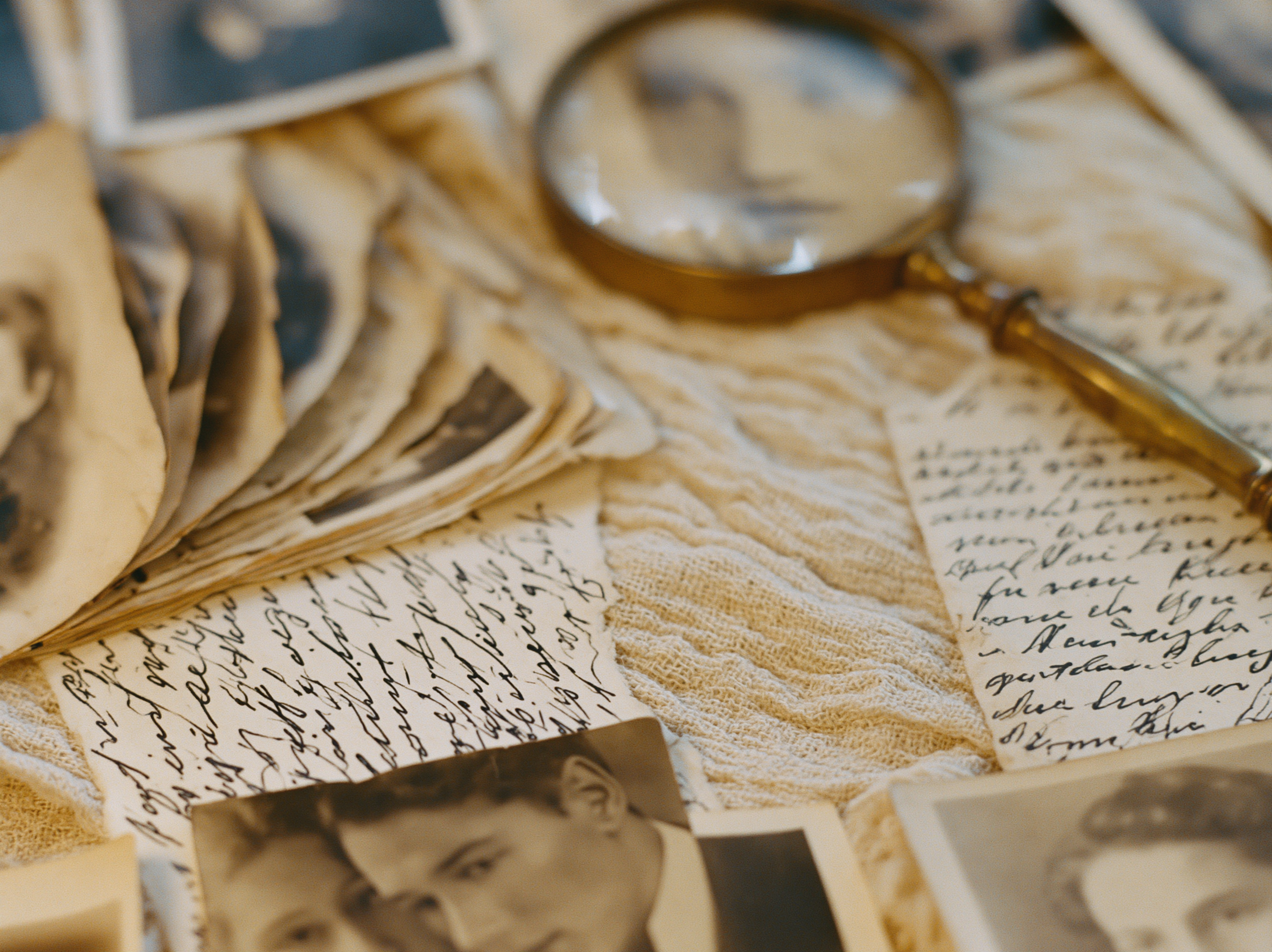 Old sepia family photographs and handwritten letters with a brass magnifier