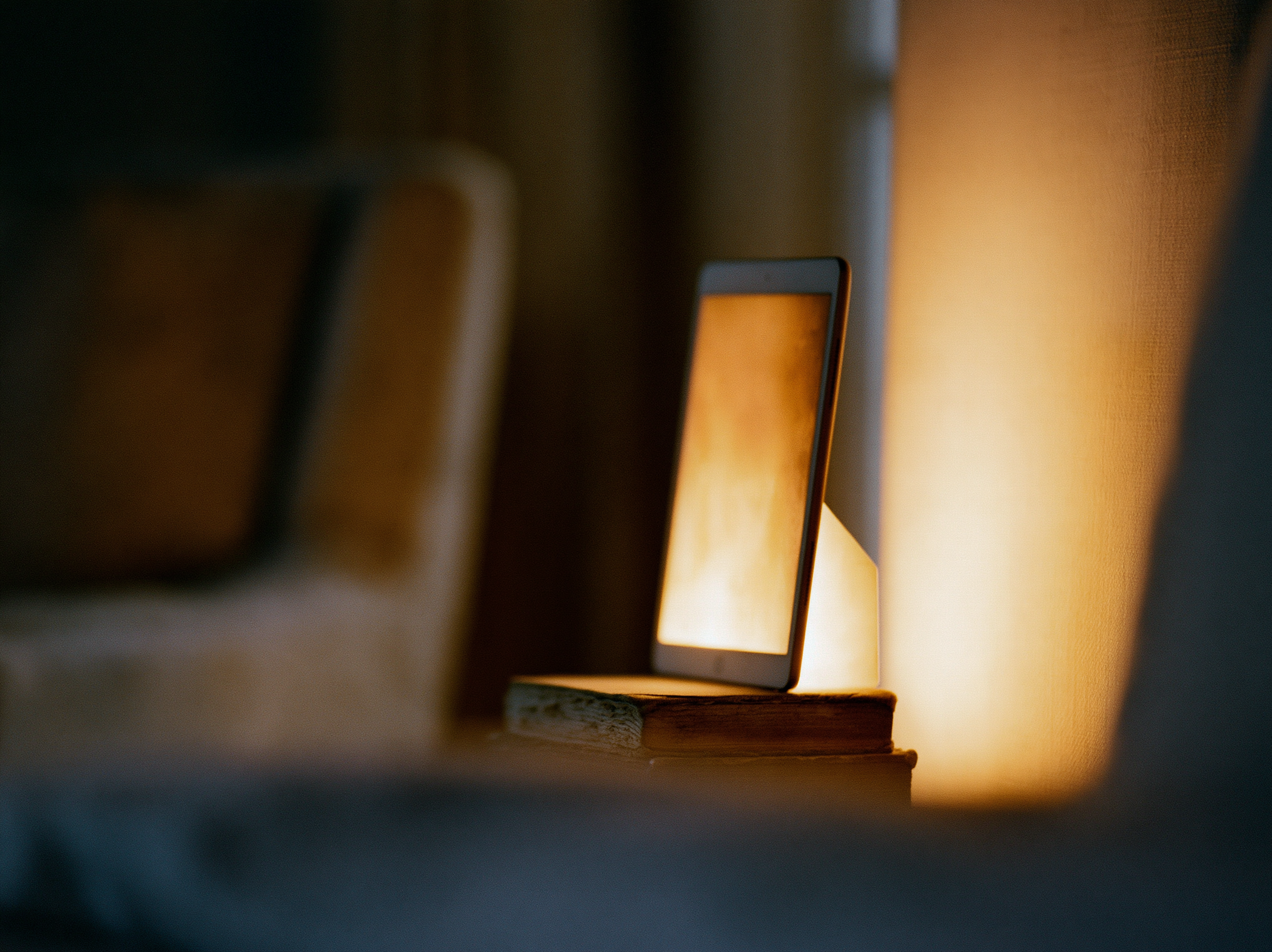 A softly glowing frame resting on a small stack of books at dusk, warm and quiet